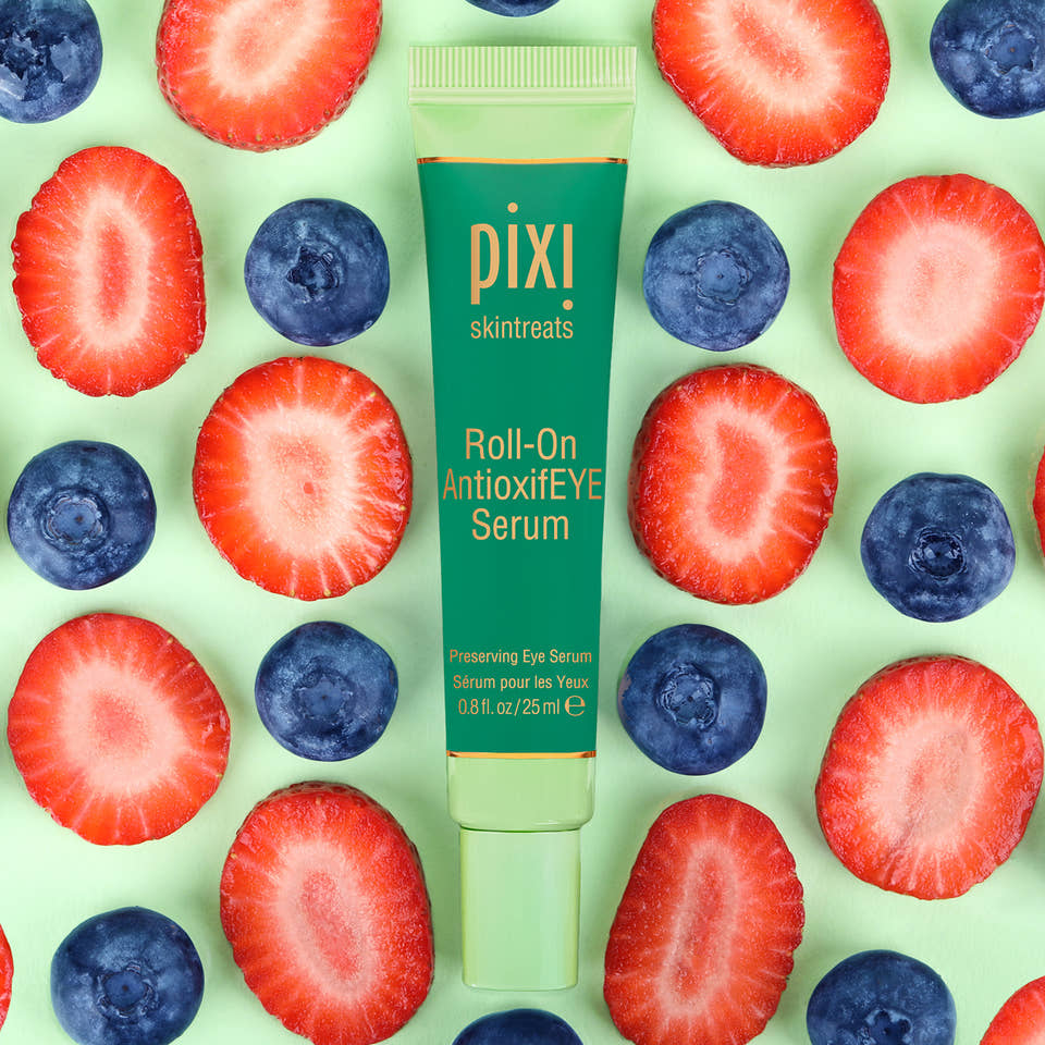  PIXI Roll-On AntioxidEYE Serum surrounded by sliced strawberries and blueberries on a green background view 1